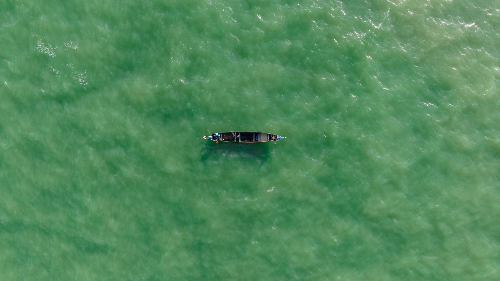 Perahu kecil di atas laut hijau kebiruan